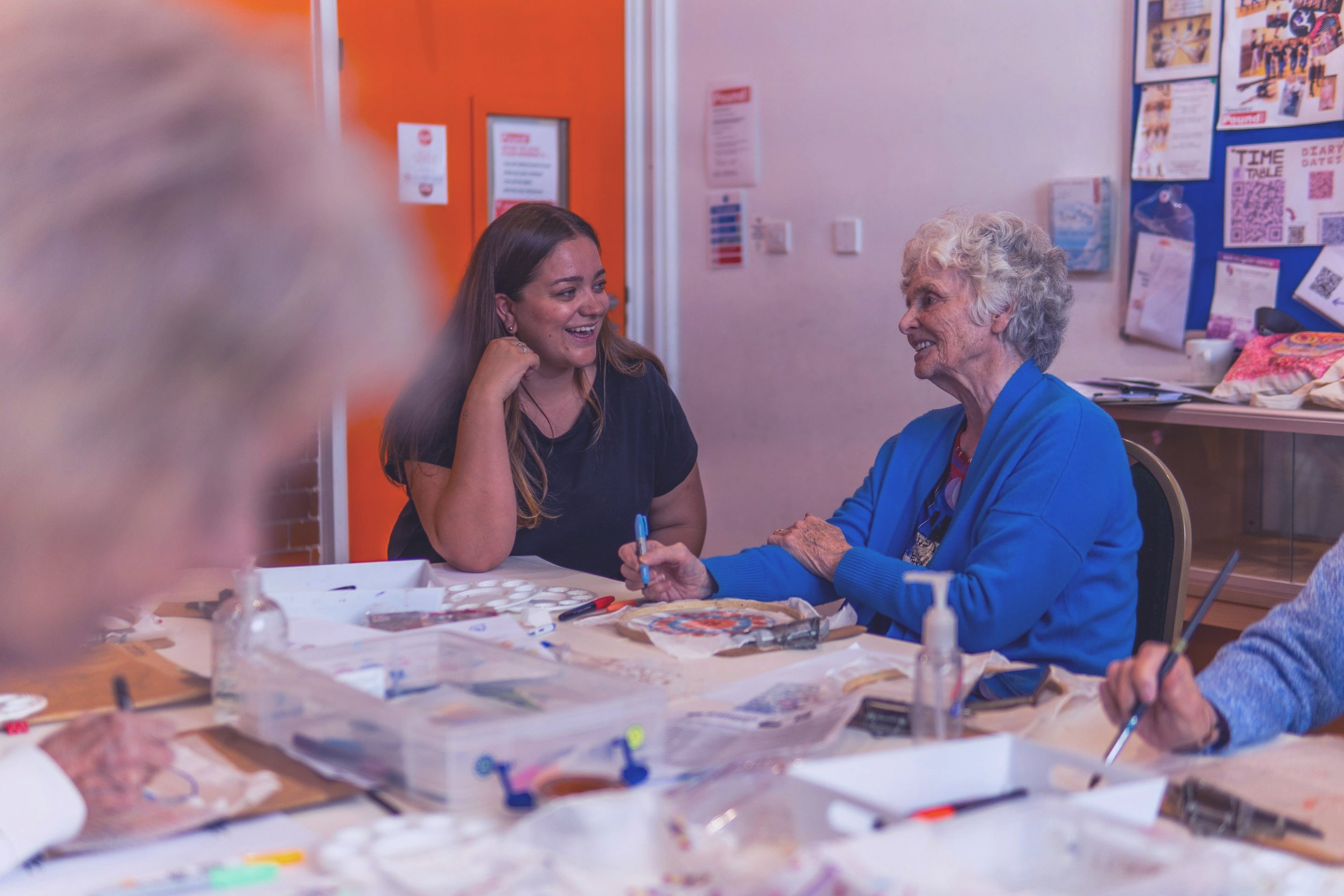 Mujer joven y mujer mayor conversando en un taller de arte